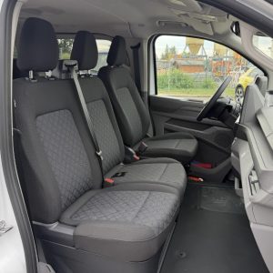 Innenraum eines Fahrzeugs mit drei vorderen Sitzen in Stoff mit Muster und Sicherheitsgurten