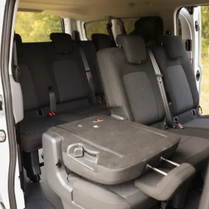 Innenraum eines VW 9-Sitzers mit geöffnetem Seiteneinstieg, mehreren Sitzreihen und einem hochgeklappten Sitz