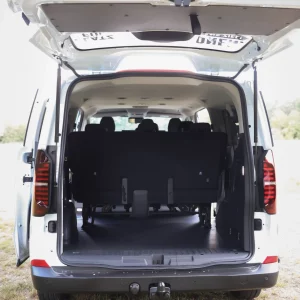 Offener Kofferraum eines VW 9-Sitzers mit Blick auf die hinteren Sitzreihen und geöffneter Heckklappe auf einer Wiese